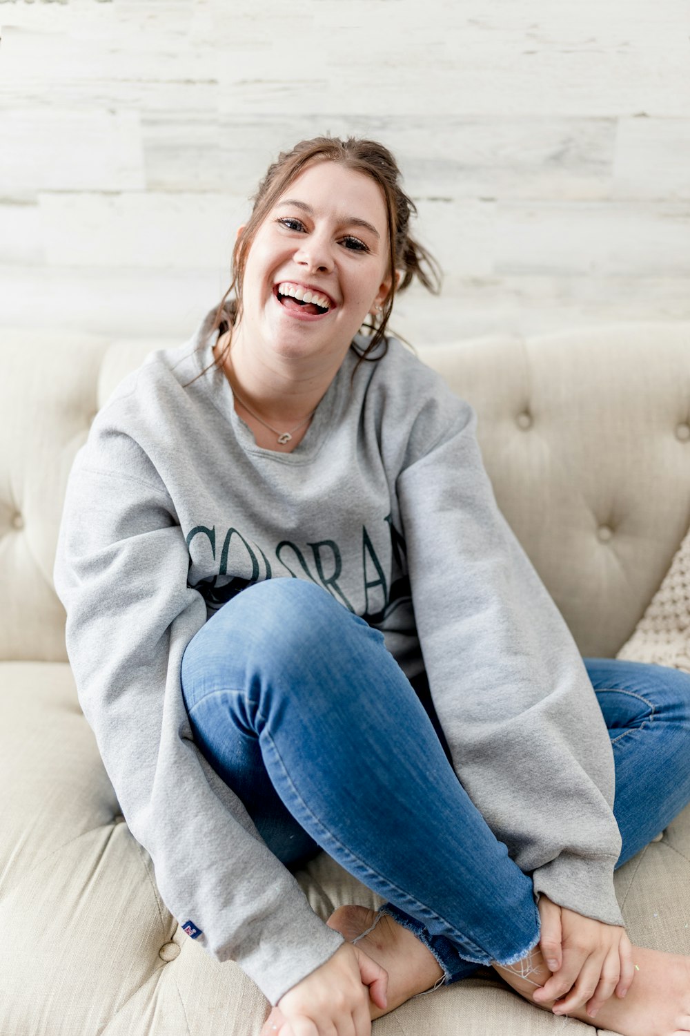 Eine Frau sitzt lachend auf einer Couch