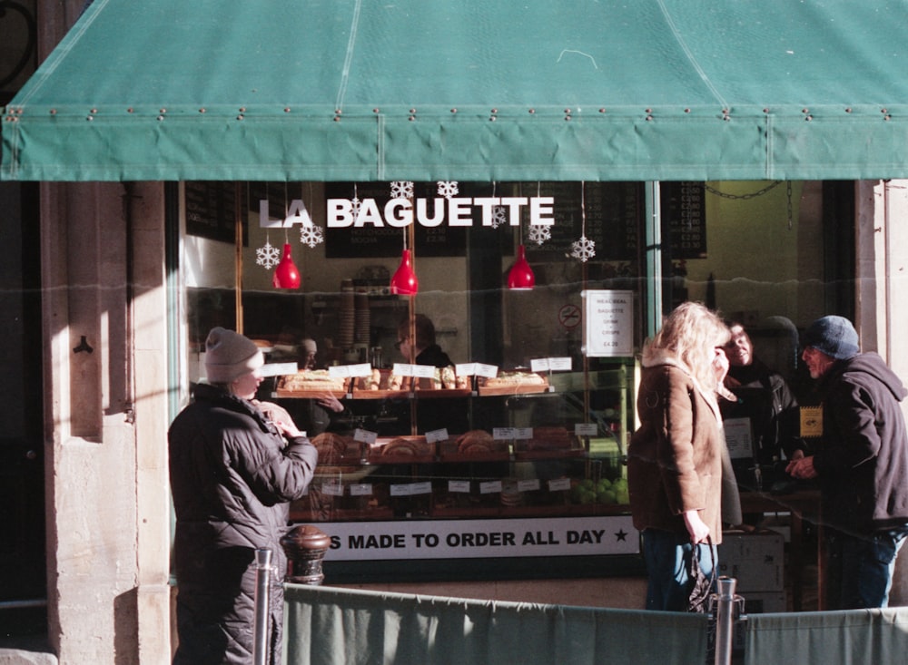 Un gruppo di persone in piedi fuori da una panetteria