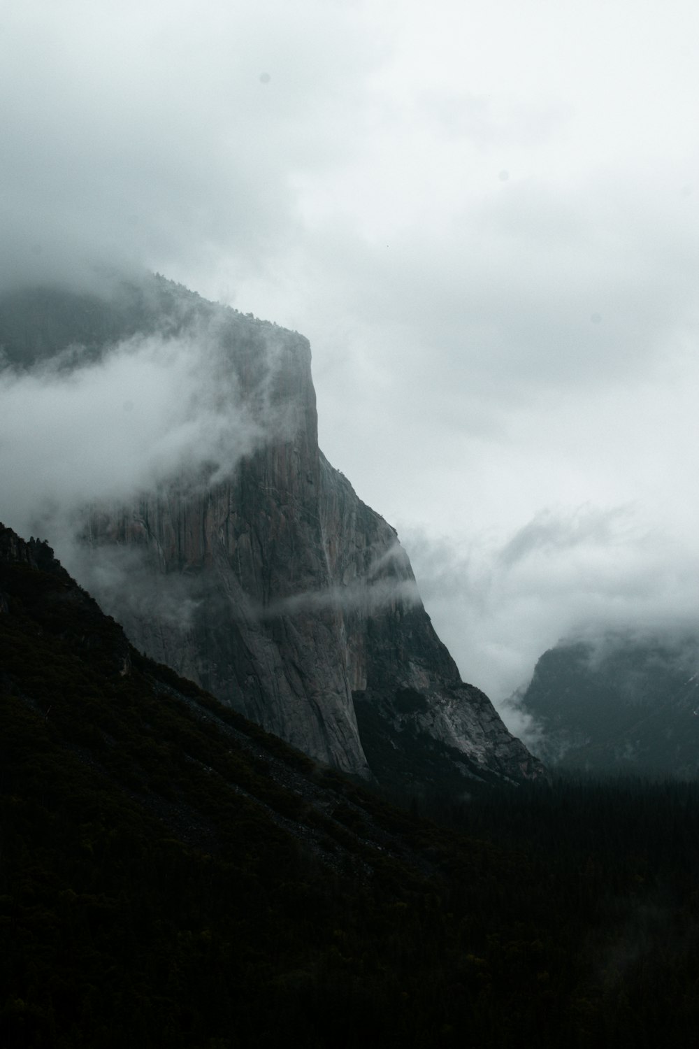 a mountain covered in fog and clouds on a cloudy day