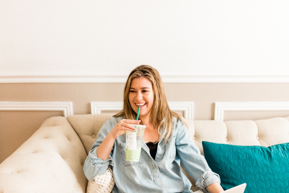 a woman sitting on a couch drinking a drink