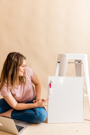 A cheerful woman teaching an online course with bright mint green and yellow accents in the background.