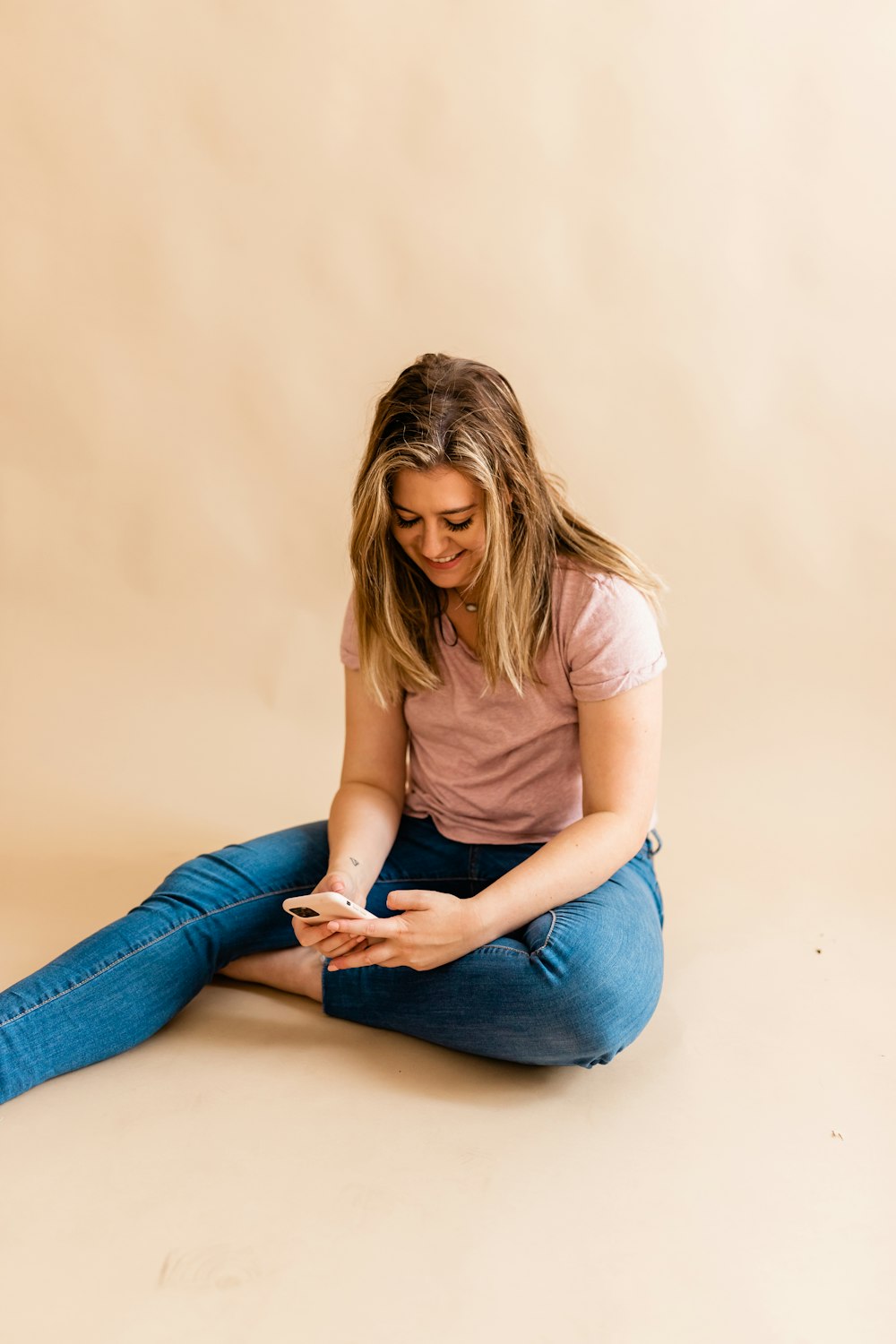 a woman sitting on the floor looking at her phone
