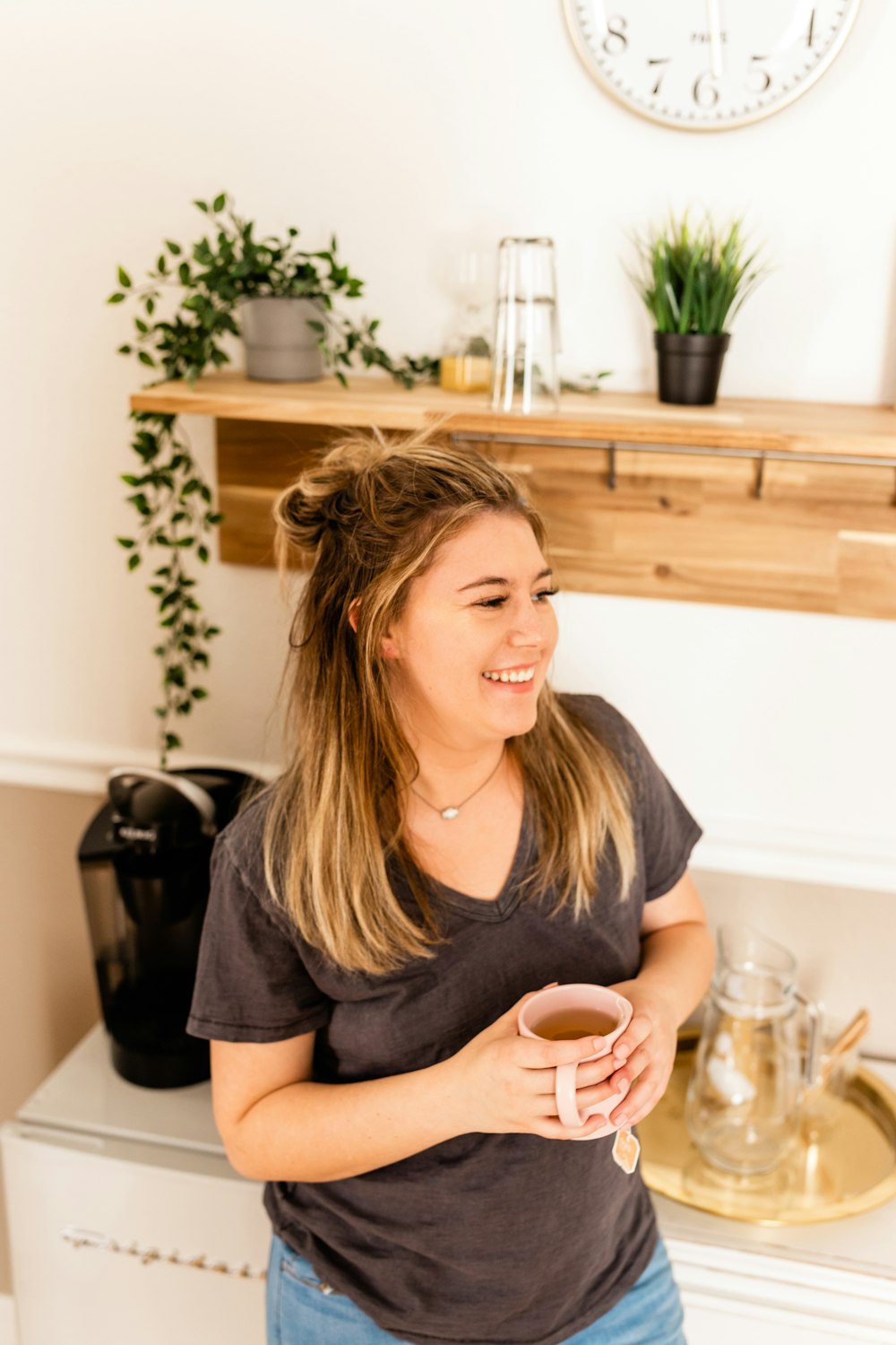 a woman standing in a kitchen holding a cup of coffee