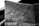 A close-up black and white photograph of a detailed topographic map. The map features contour lines, place names, and various markings indicating geographical features. It appears to be held in a hand, positioned at an angle that highlights its texture and intricate details.