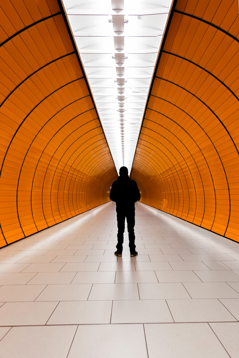 a man standing in a tunnel with orange walls