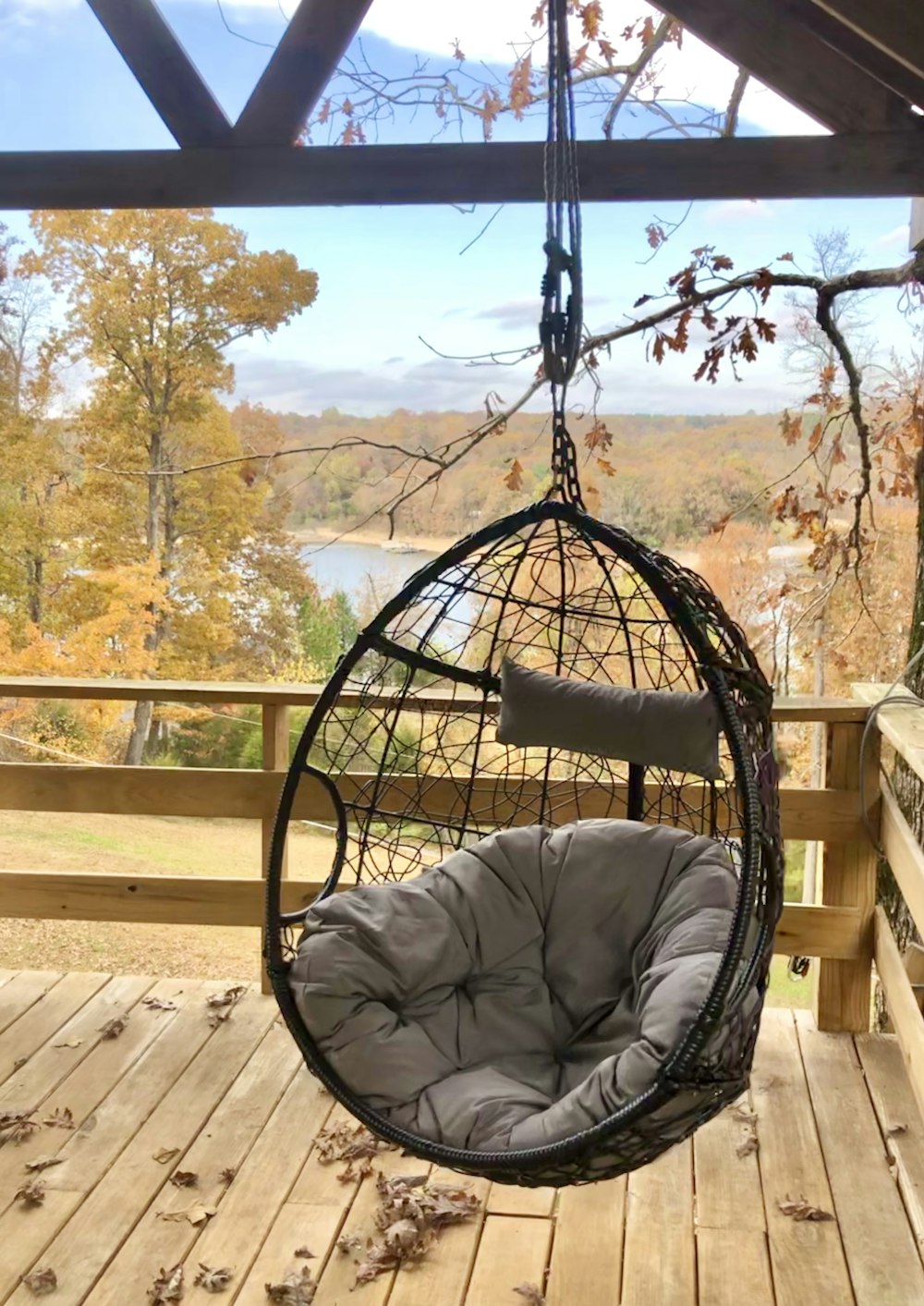 a swing chair hanging from a wooden porch