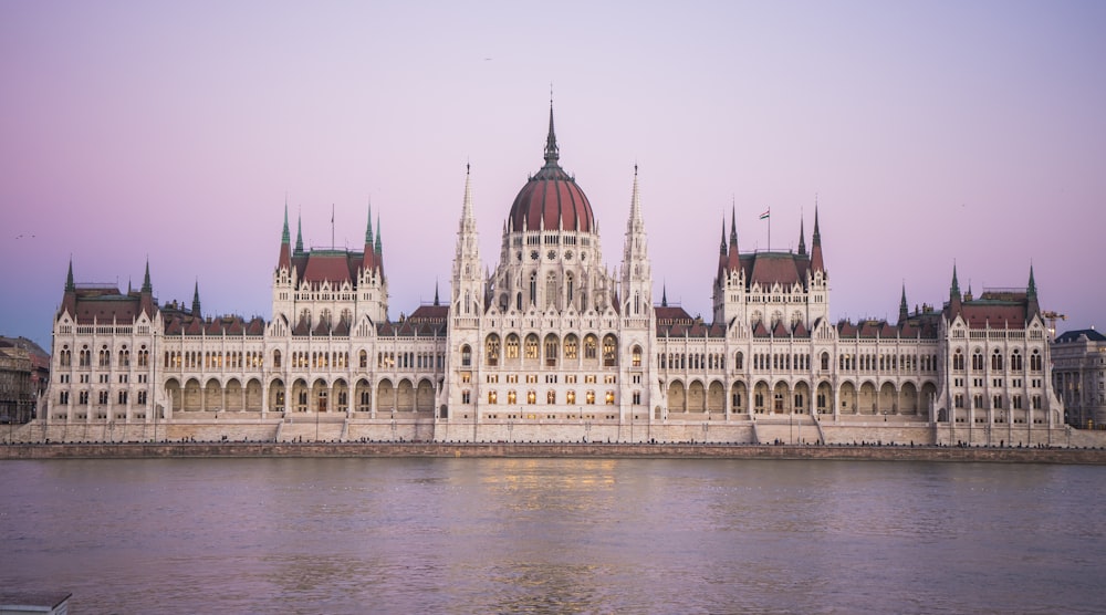 a large white building with a red dome next to a body of water