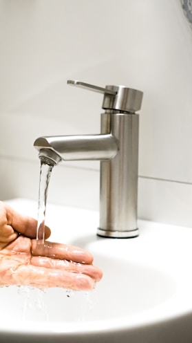 a person washing their hands under a faucet