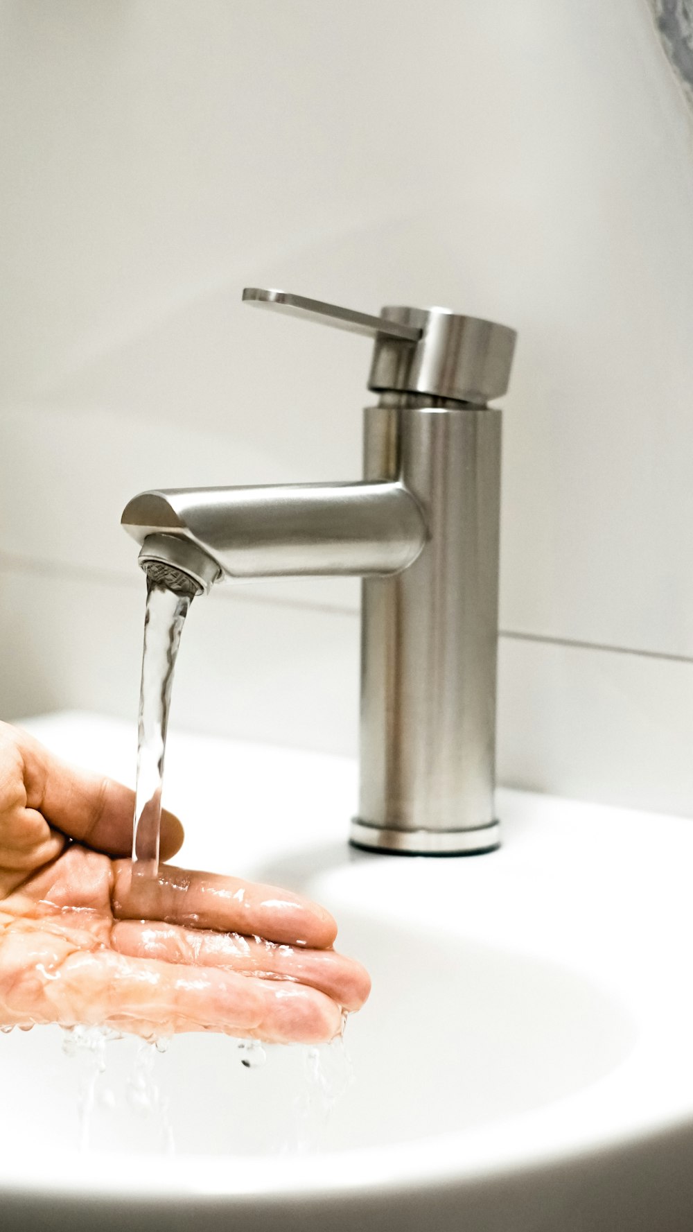 a person washing their hands under a faucet