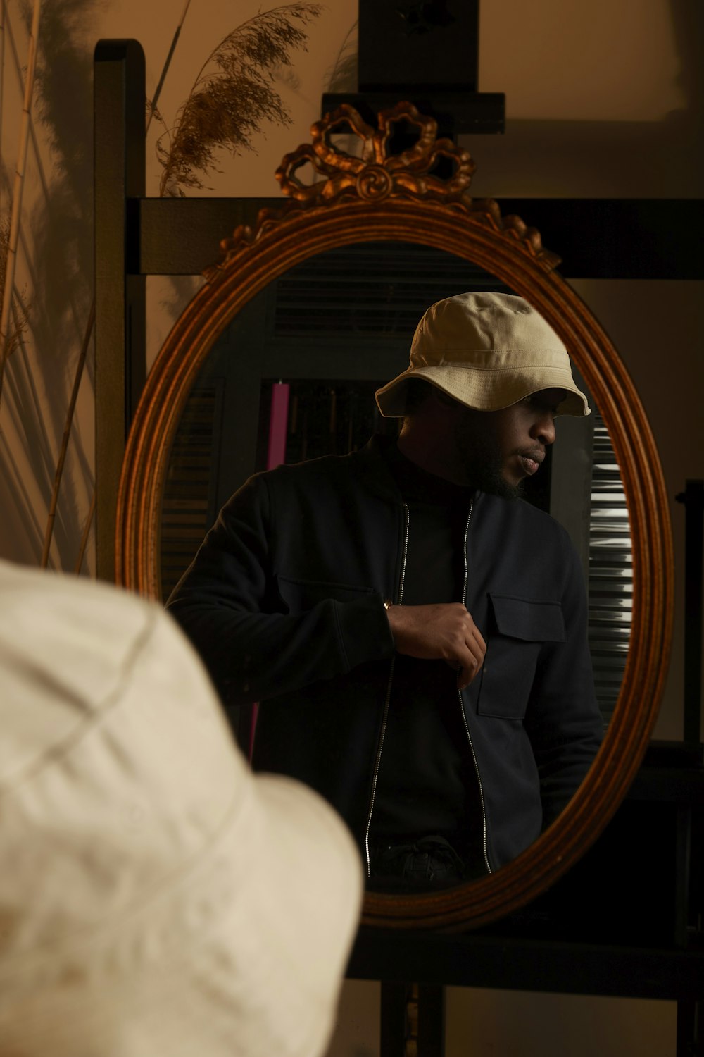 a man in a hat looking at himself in a mirror