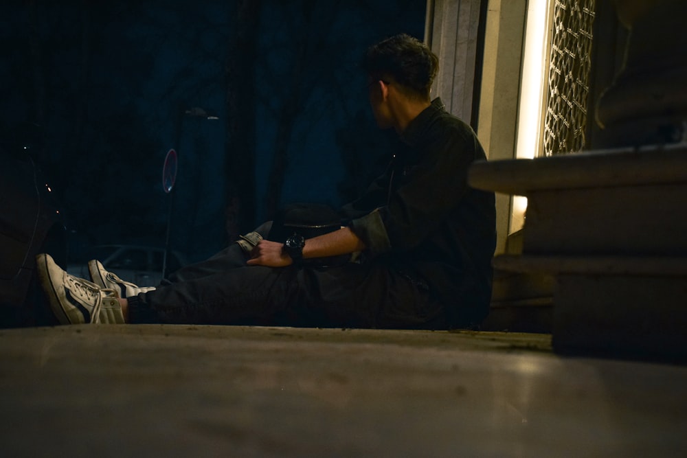 a man sitting on the ground looking at his cell phone