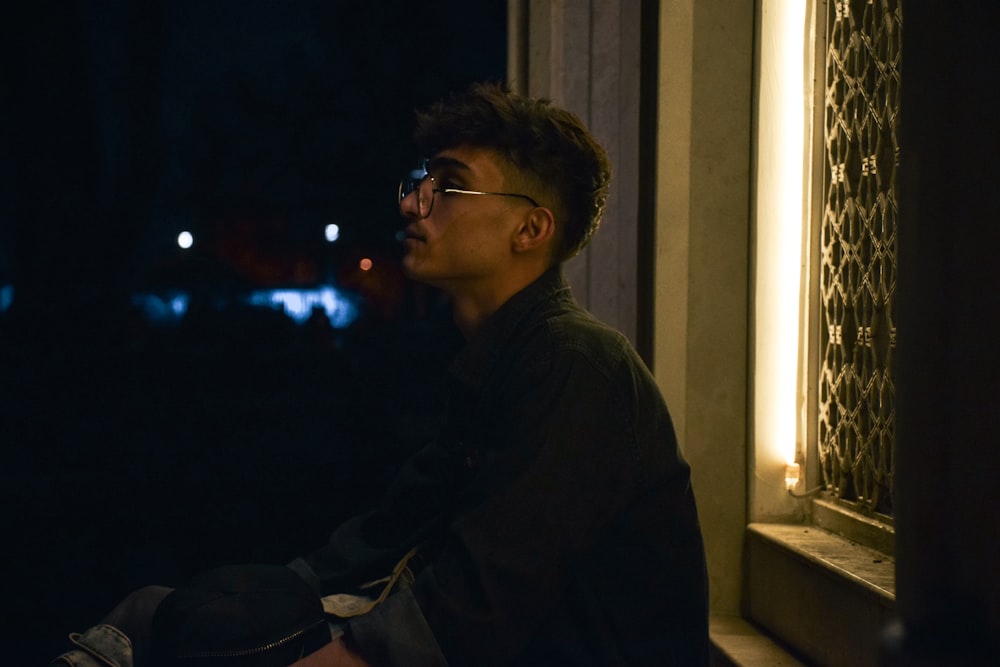 a man sitting on a window sill at night