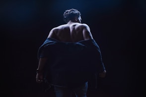 a woman walking in the dark with her back to the camera