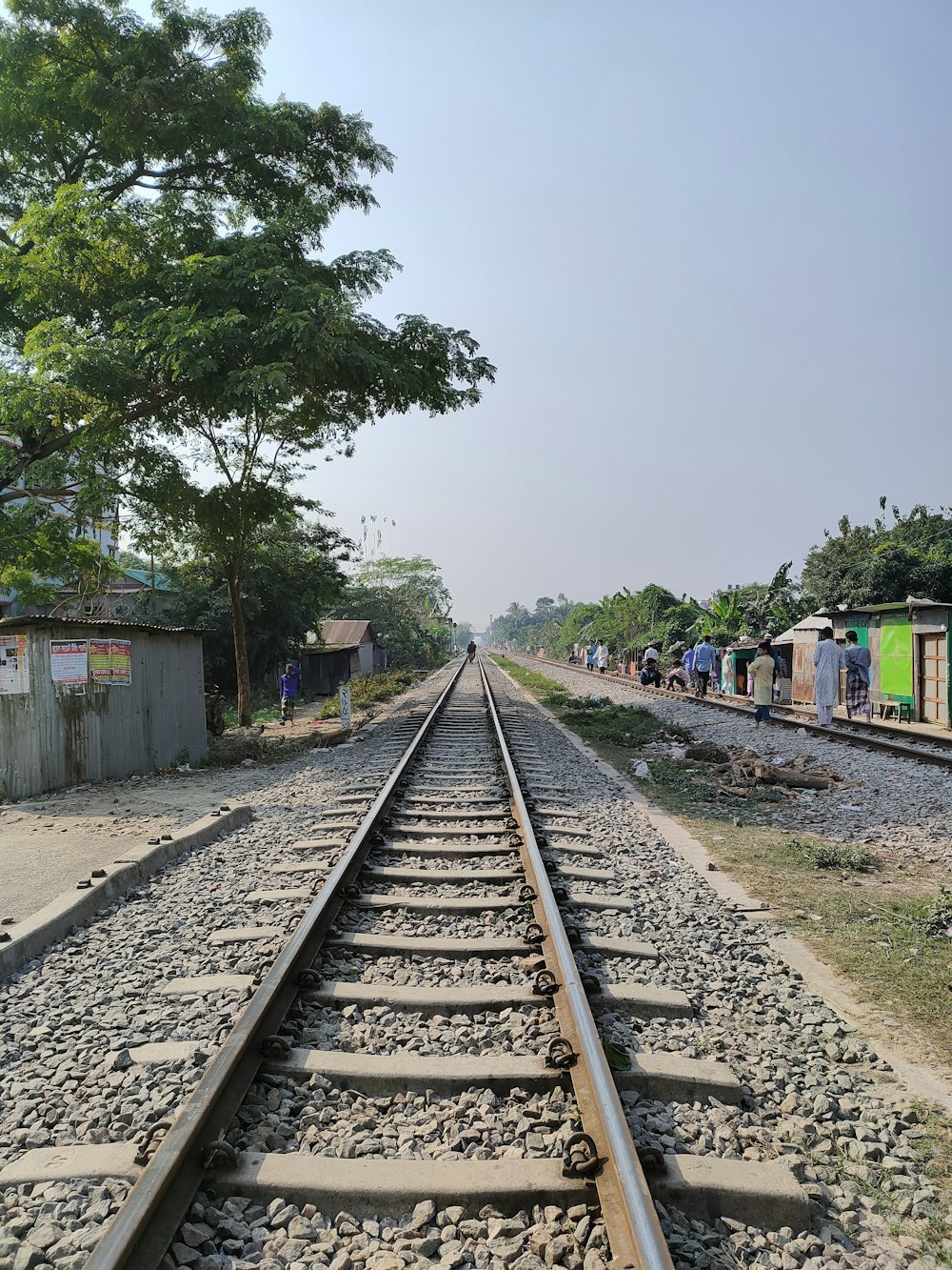 a train track with people standing on the side of it