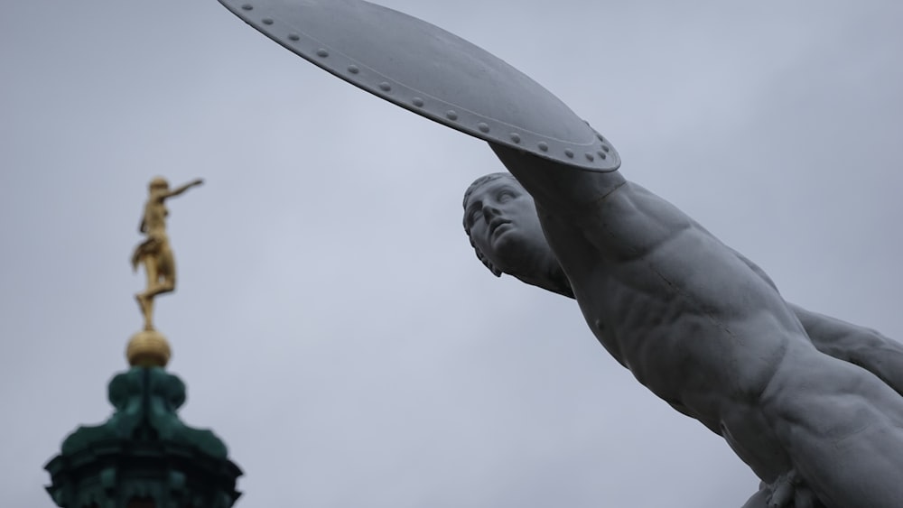 Una estatua de un hombre sosteniendo un frisbee junto a una estatua de un