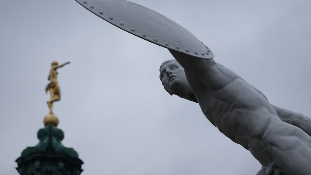 a statue of a man holding a frisbee next to a statue of a