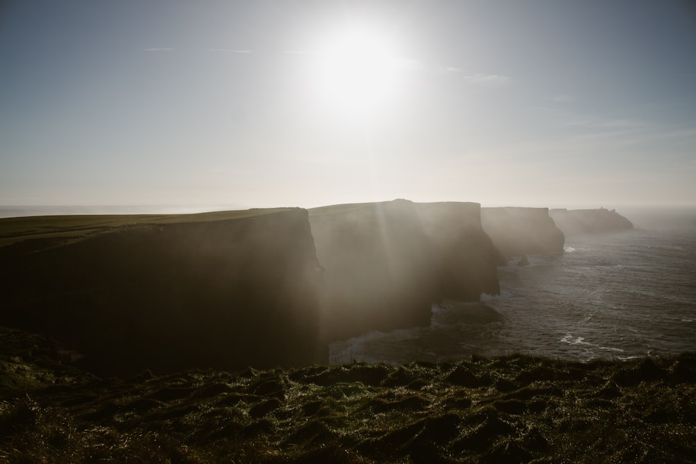 the sun is shining over the cliffs of the ocean