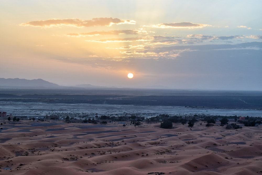 the sun is setting over a desert landscape