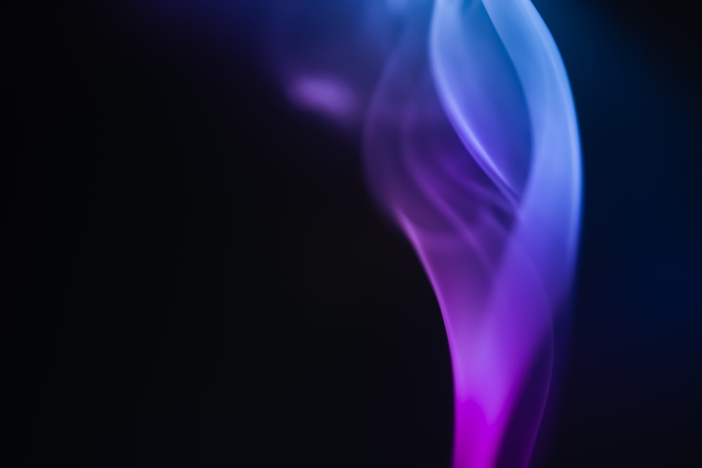 a close up of a blue and purple smoke on a black background