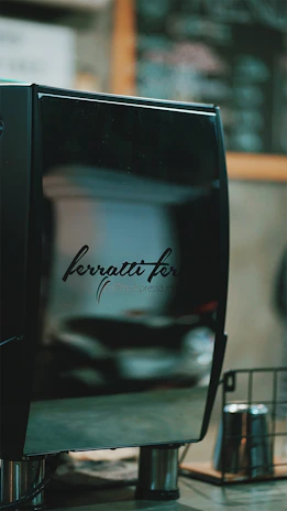 The sleek espresso machine gleaming under soft ambient lighting, ready to create the perfect cup for discerning guests.