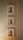 Three framed illustrations of different dog breeds are displayed vertically on a neutral-colored wall. Each artwork features a detailed depiction of a dog with a unique style and coat.