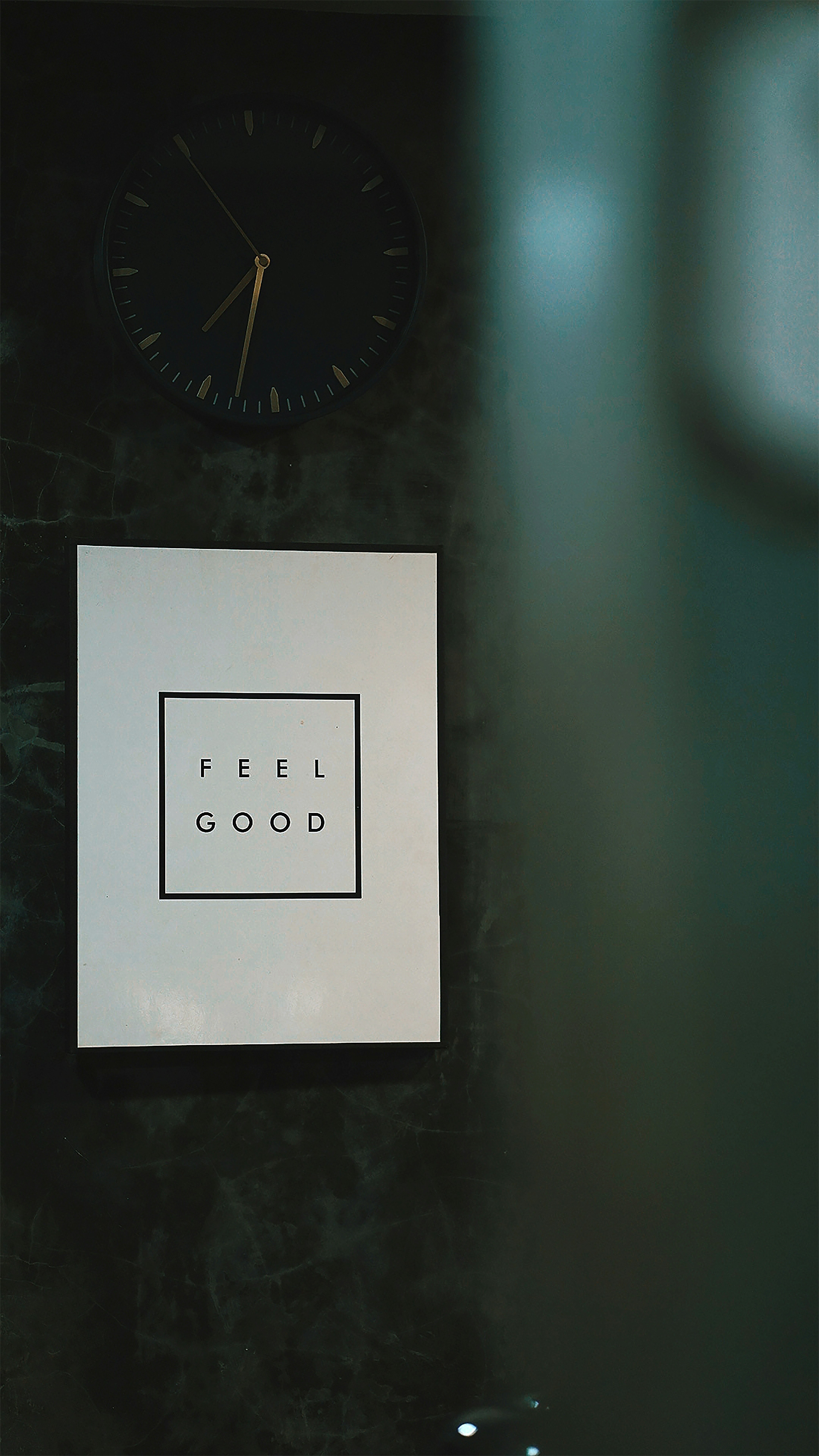 a clock on a wall next to a sign that says feel good