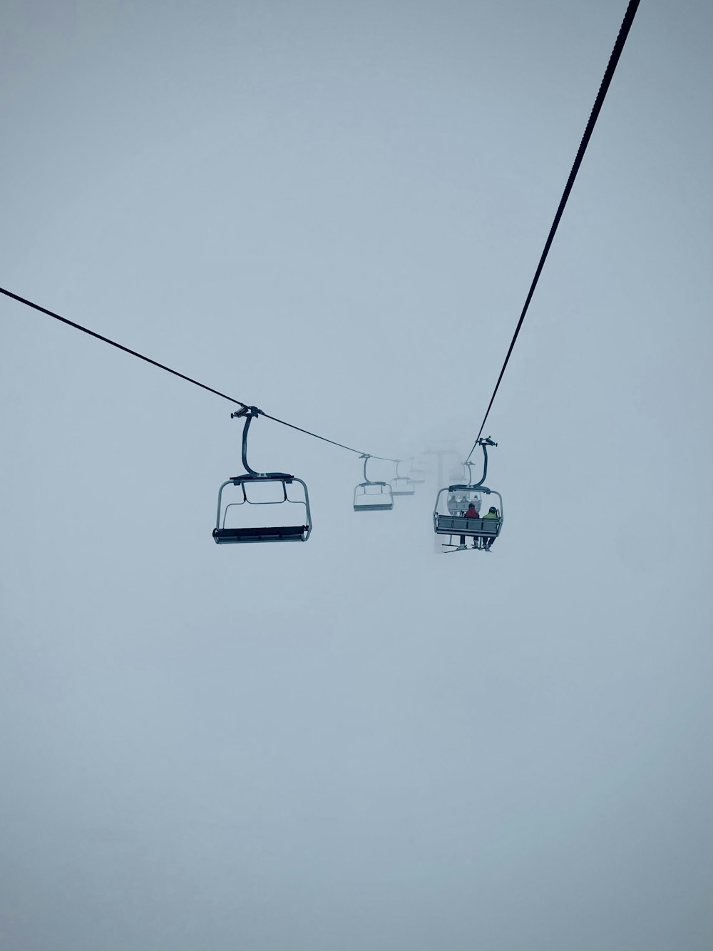 a ski lift going up a hill in the fog