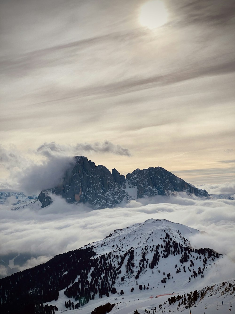 a mountain covered in snow and clouds under a cloudy sky