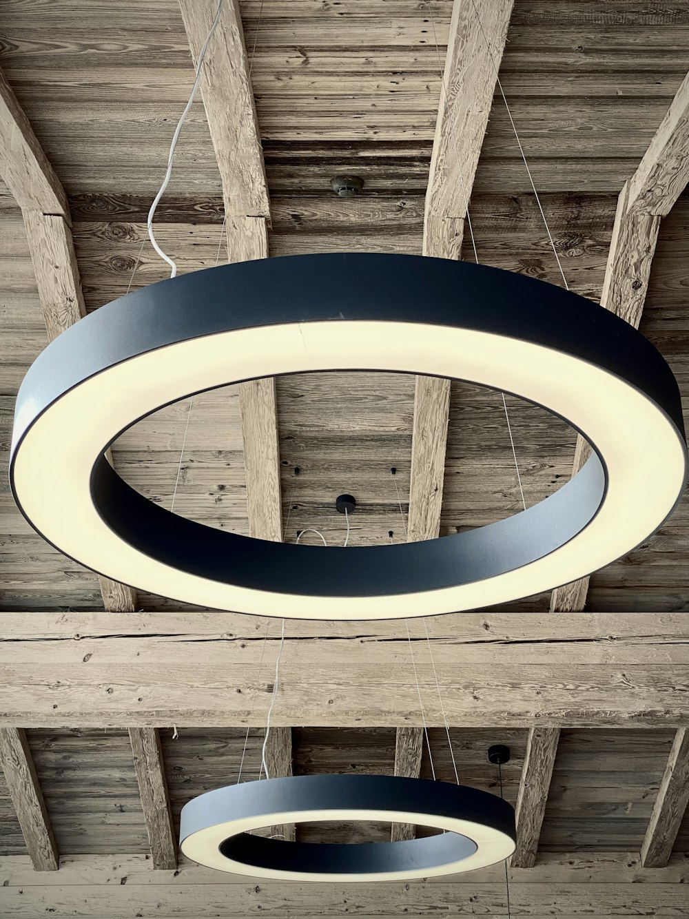 uma luminária circular pendurada em um teto de madeira