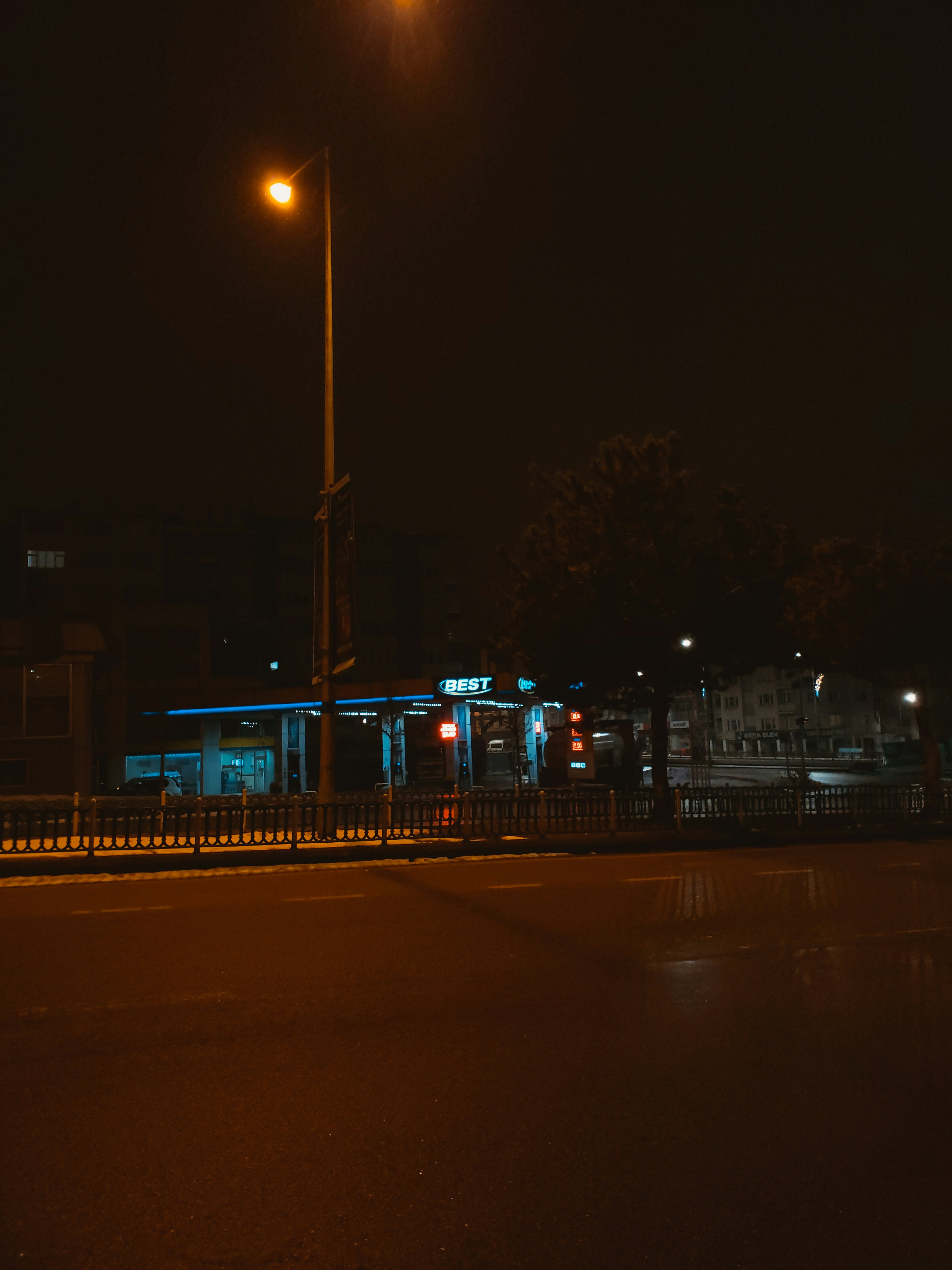 an empty street at night with a lit up bus stop