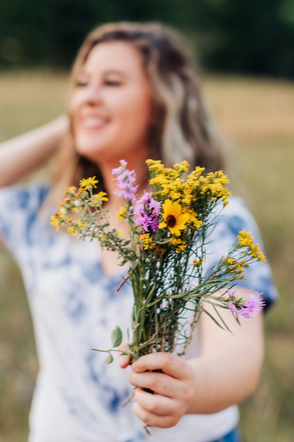 a woman holding a bouquet of wild flowers