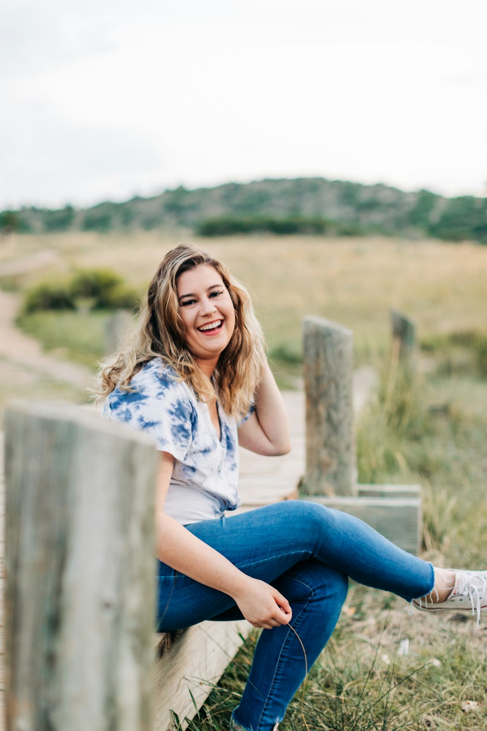 a woman sitting on a wooden bench in a field