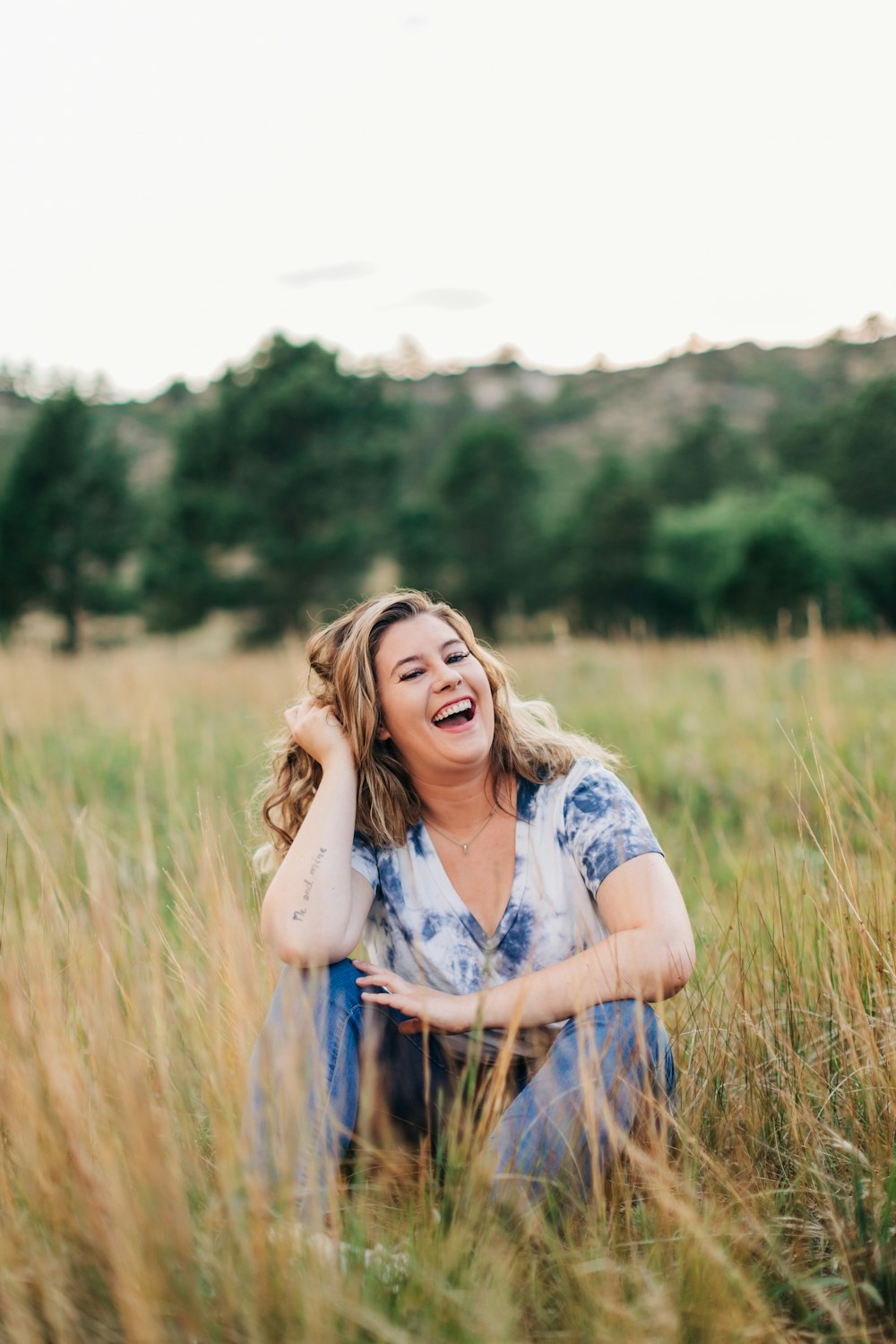 a woman laughing in a field of tall grass