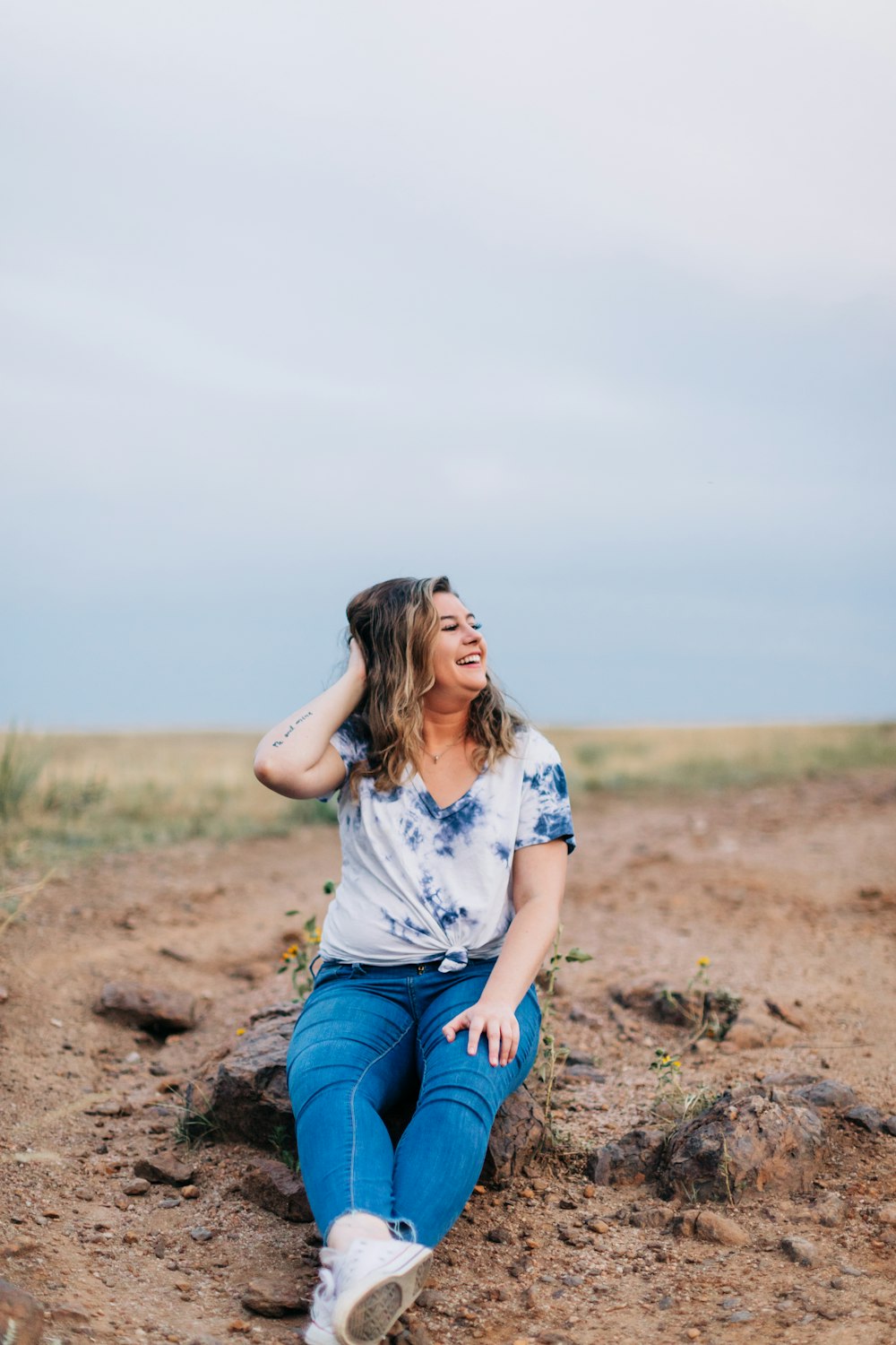 a woman sitting on the ground in a field