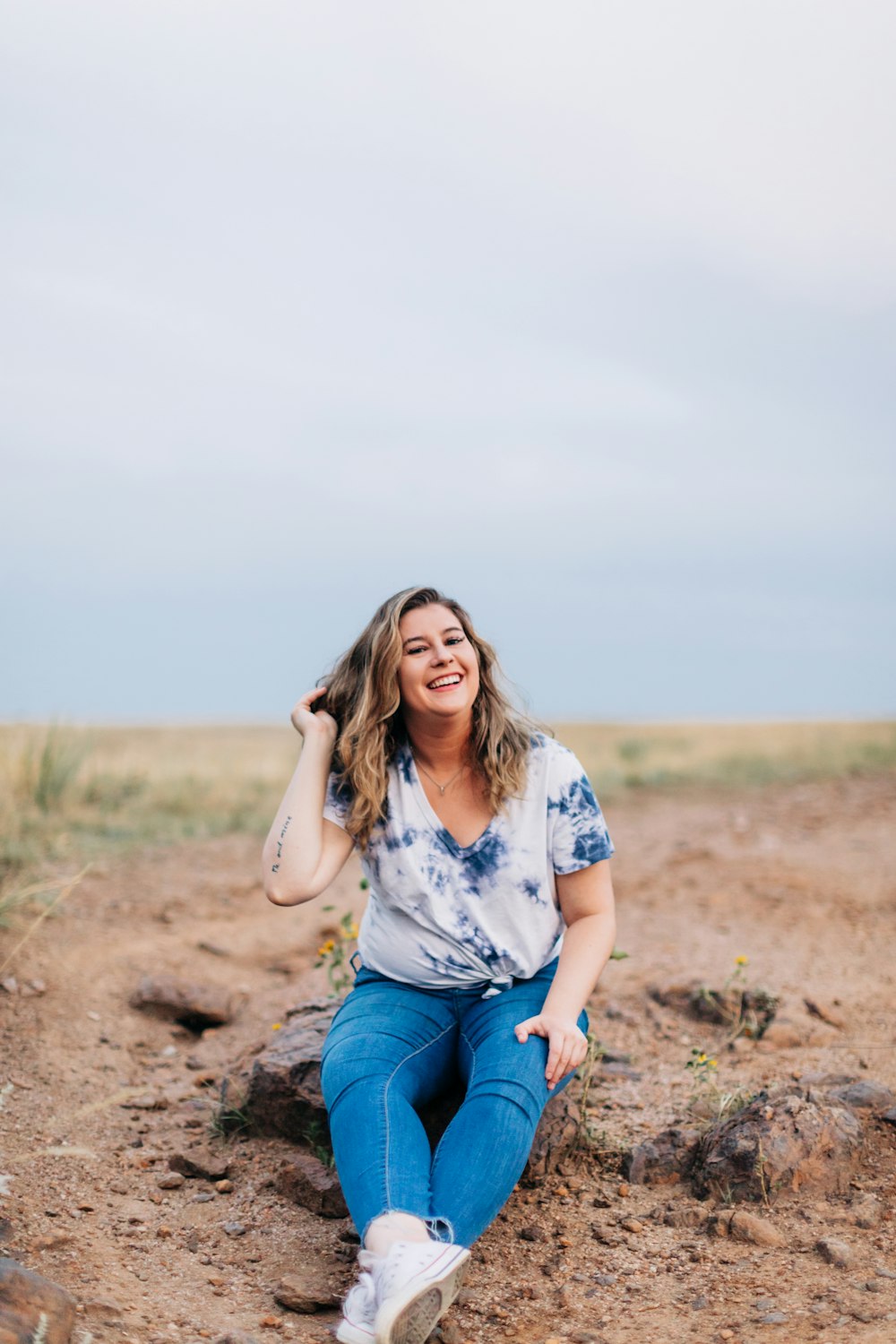 a woman sitting on a rock in the middle of a field