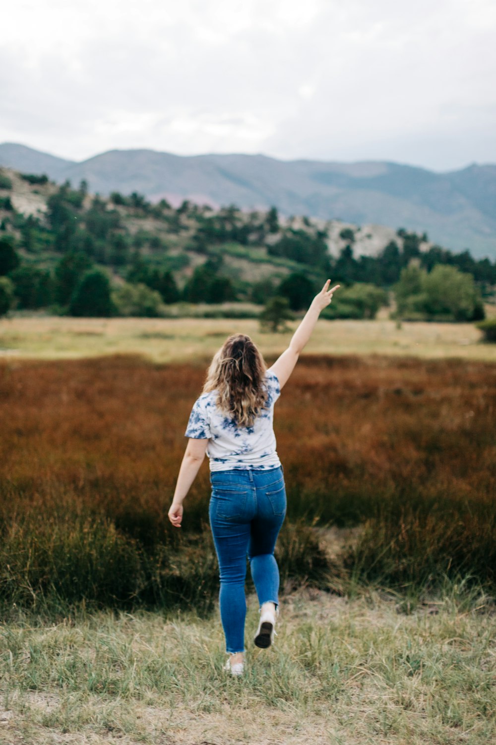 a woman in a field with her arms in the air