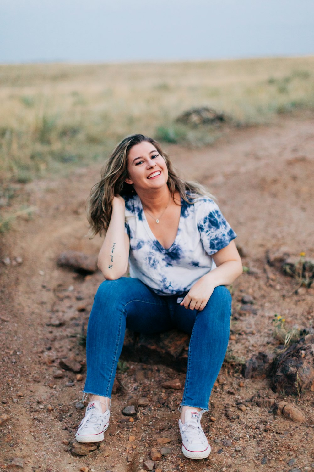 a woman sitting on a rock in the middle of a field