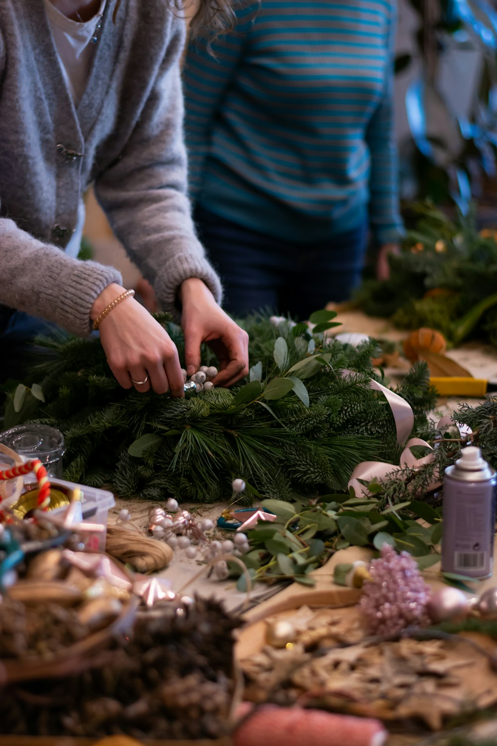 a woman is making a wreath on a table