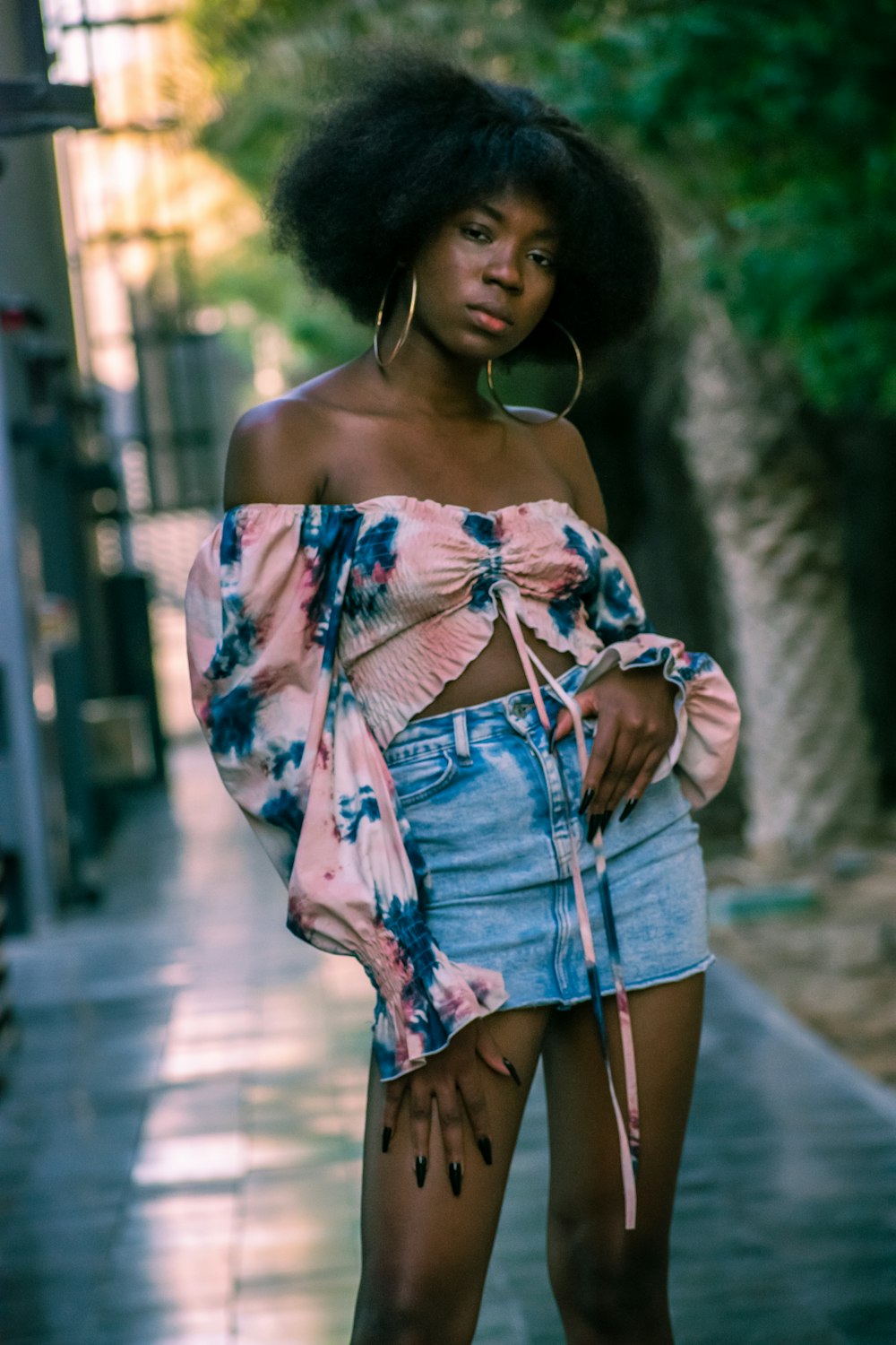 a woman standing on a sidewalk with her hands in her pockets