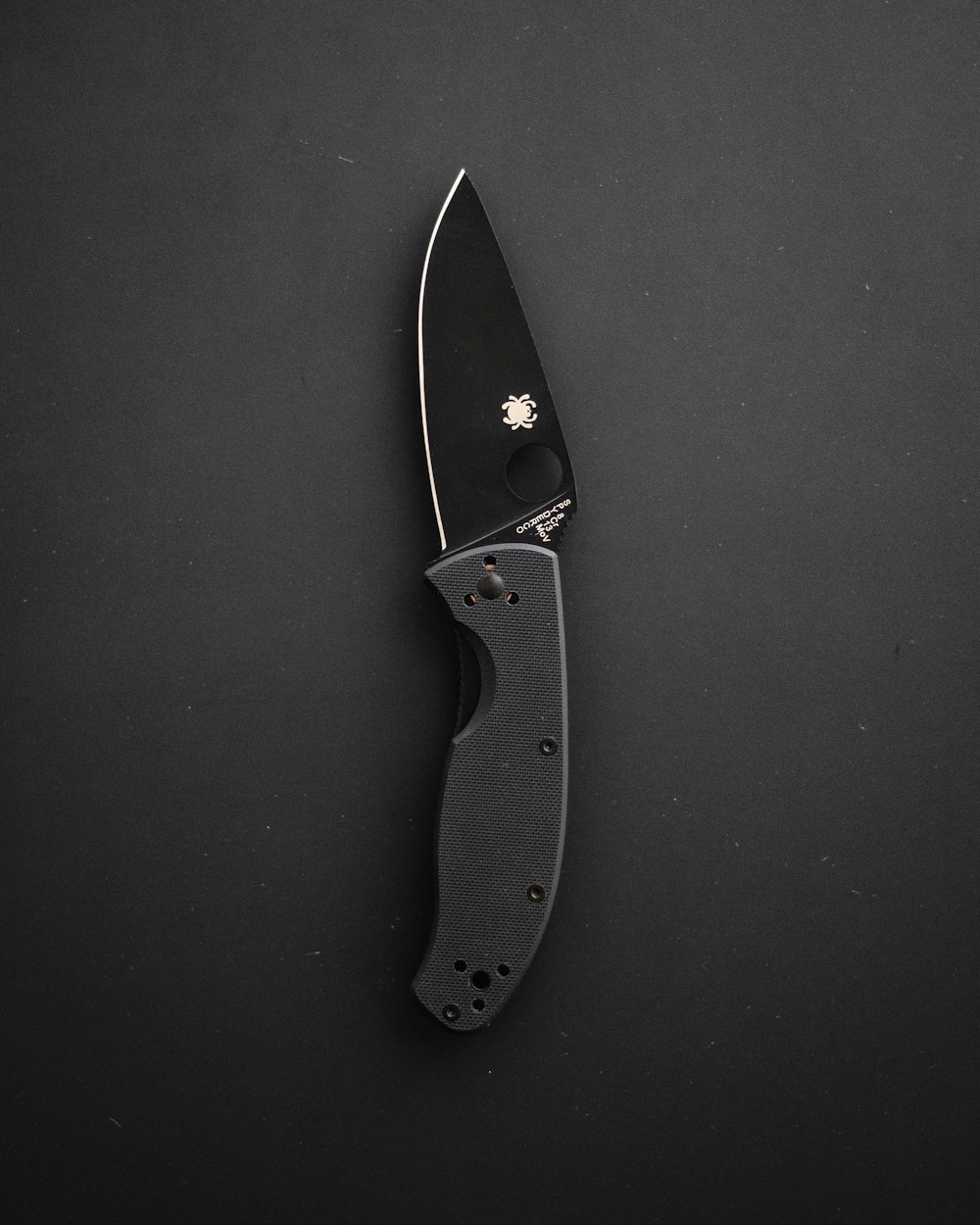 a knife with a black handle on a black surface