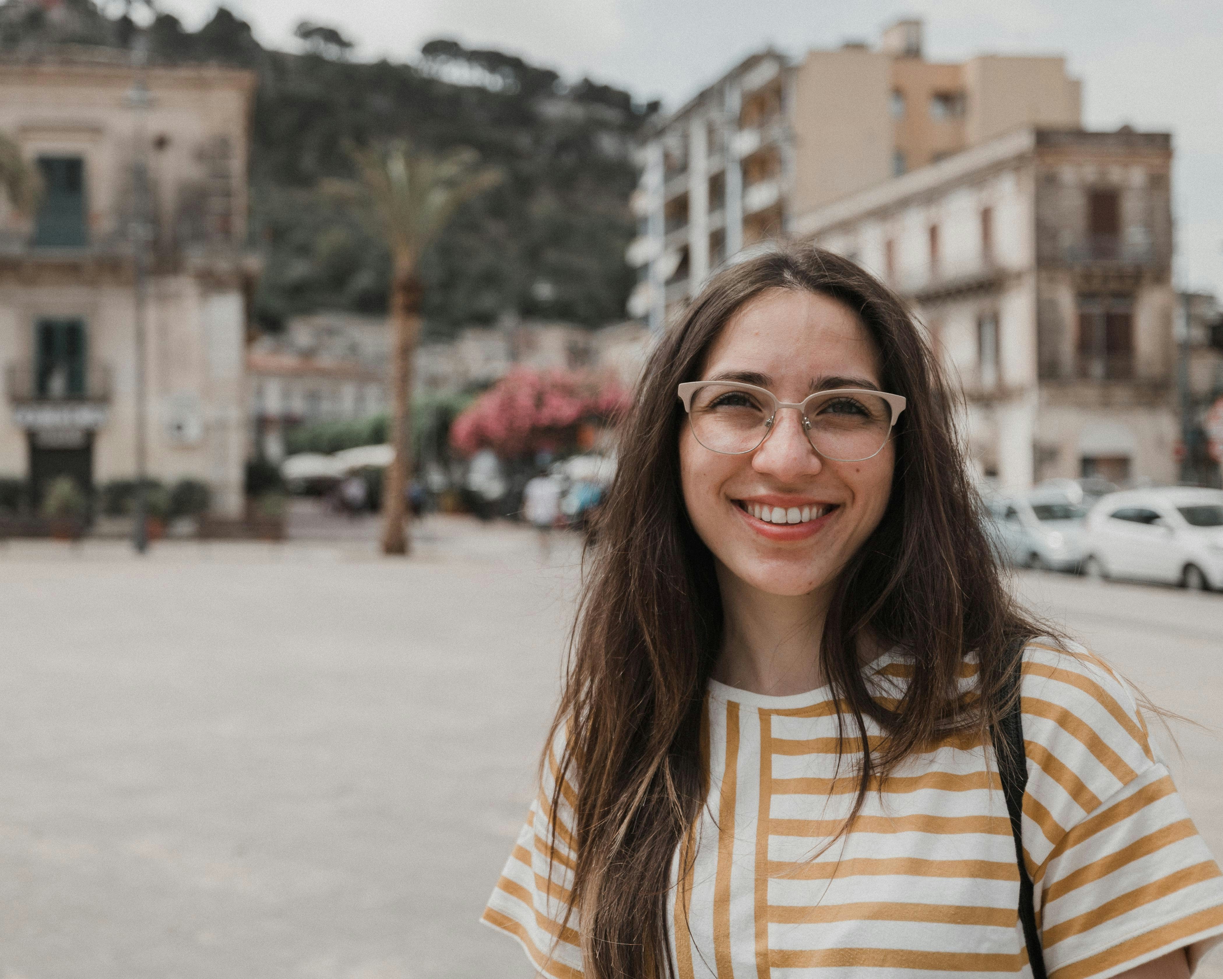 a woman wearing glasses standing in front of a street