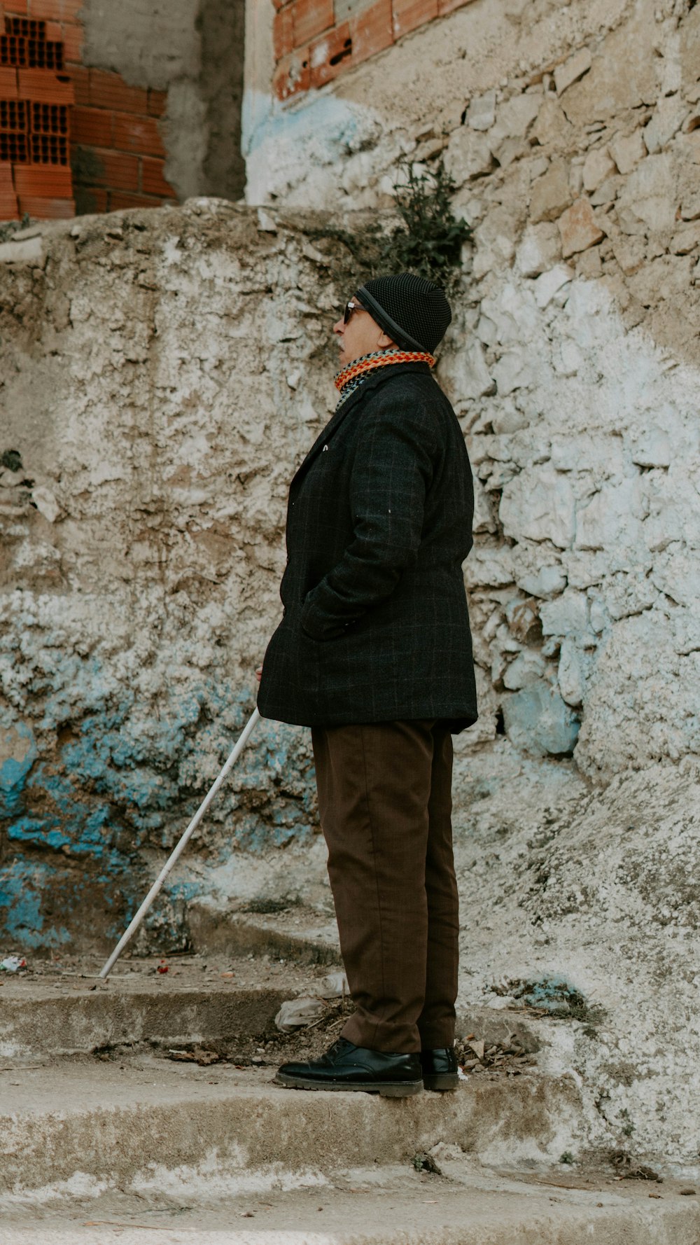 Un homme debout sur des marches avec une canne à la main