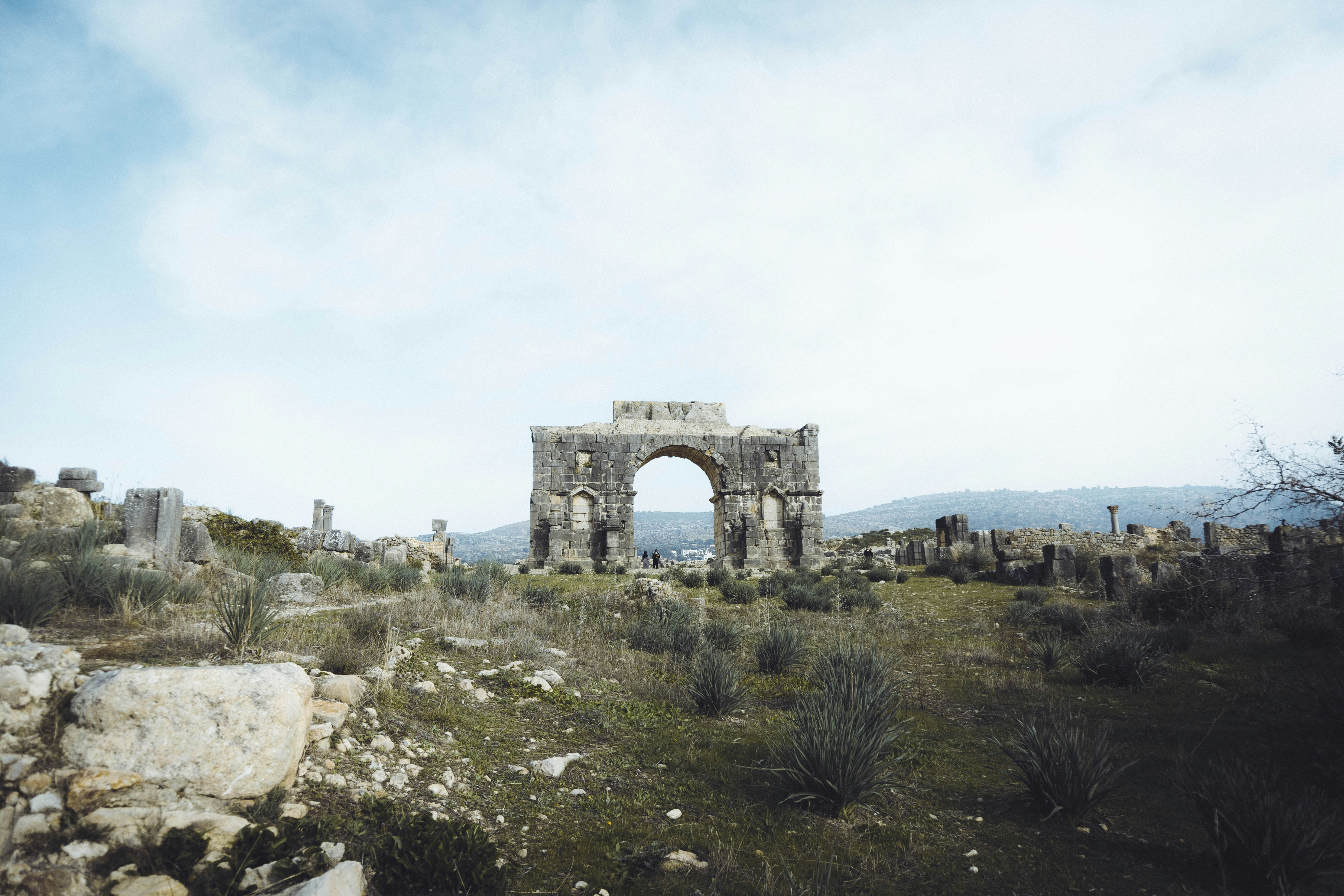 a stone arch in the middle of a field