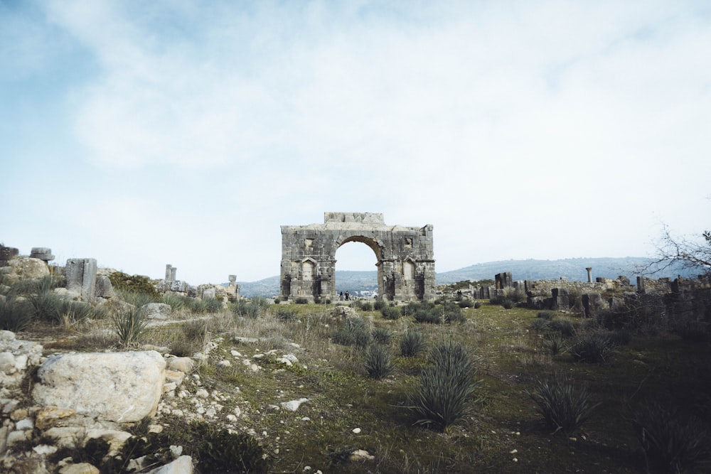 a stone arch in the middle of a field