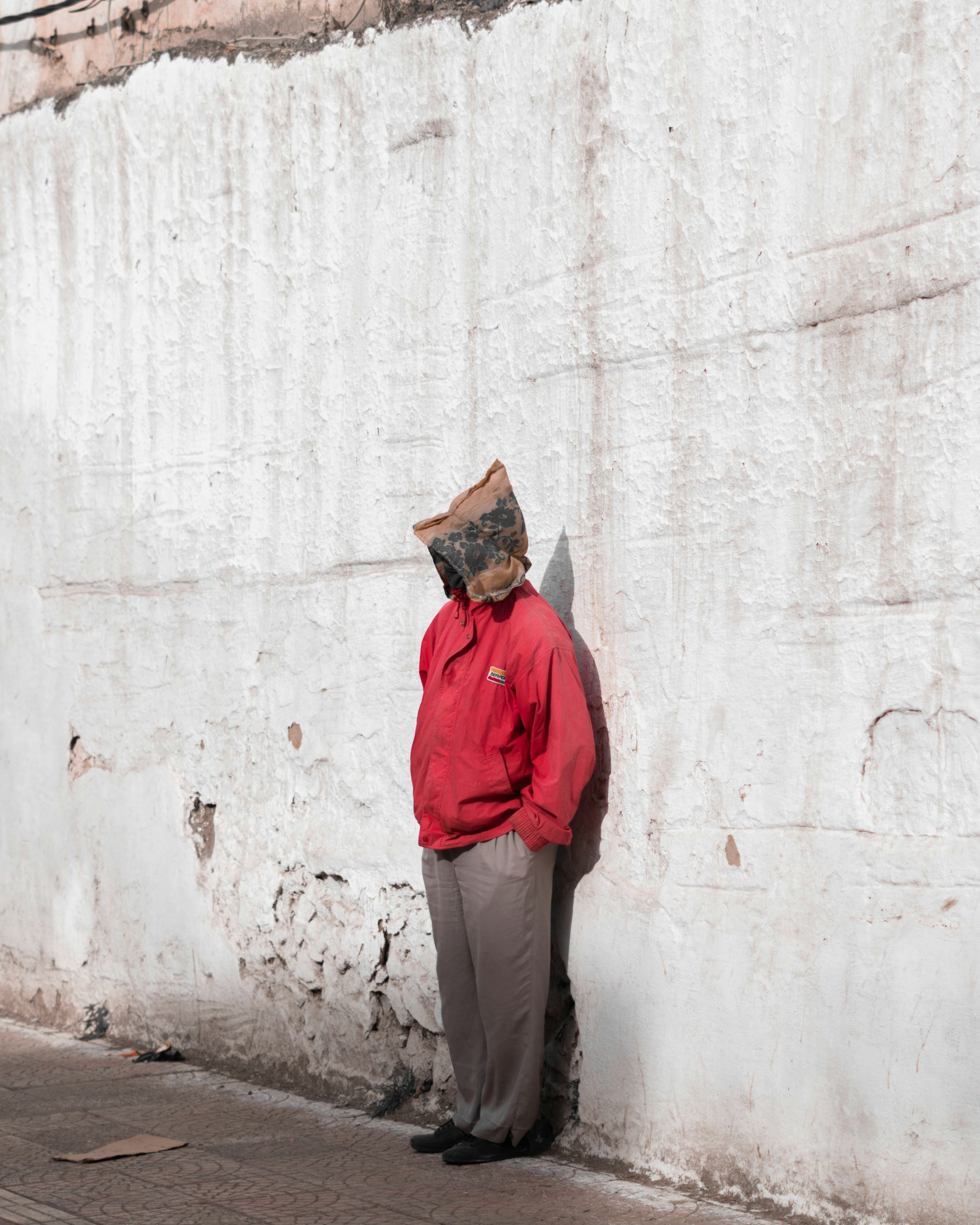 A man in a red jacket leaning against a white wall photo Free Morocco