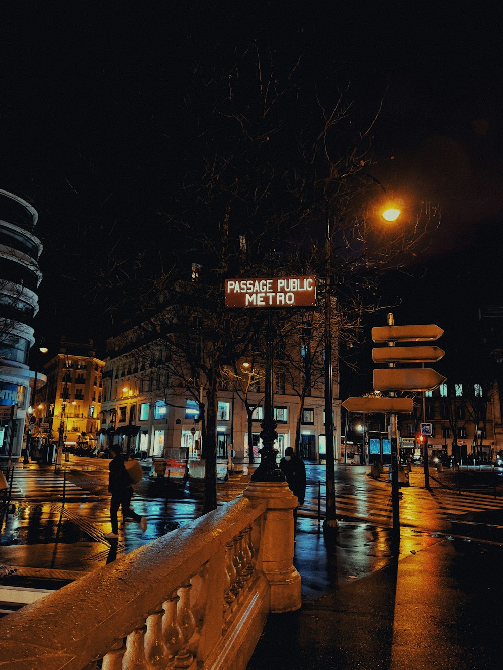 a city street at night with people walking on the sidewalk