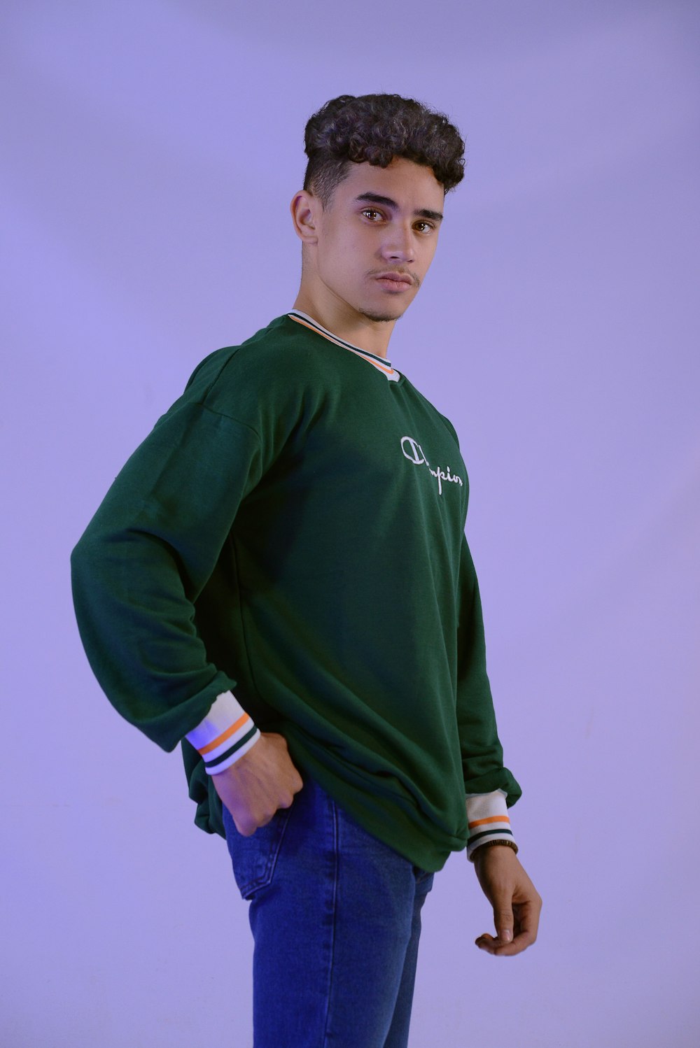 a young man in a green sweatshirt poses for a picture