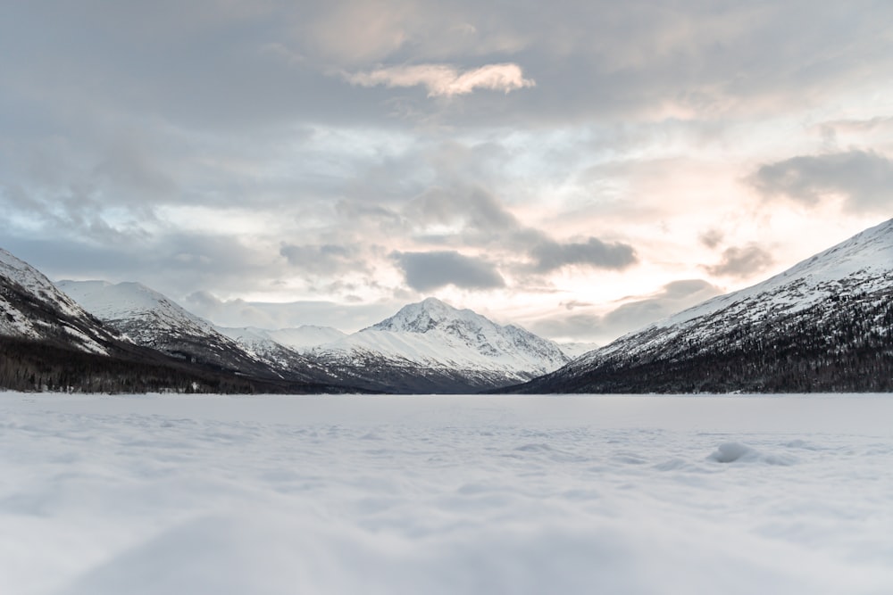 a snow covered field with mountains in the background