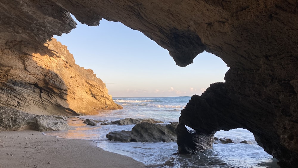 a cave on the beach with a view of the ocean