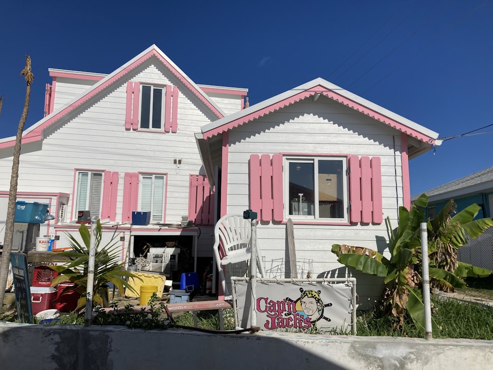 uma casa rosa e branca com persianas cor-de-rosa
